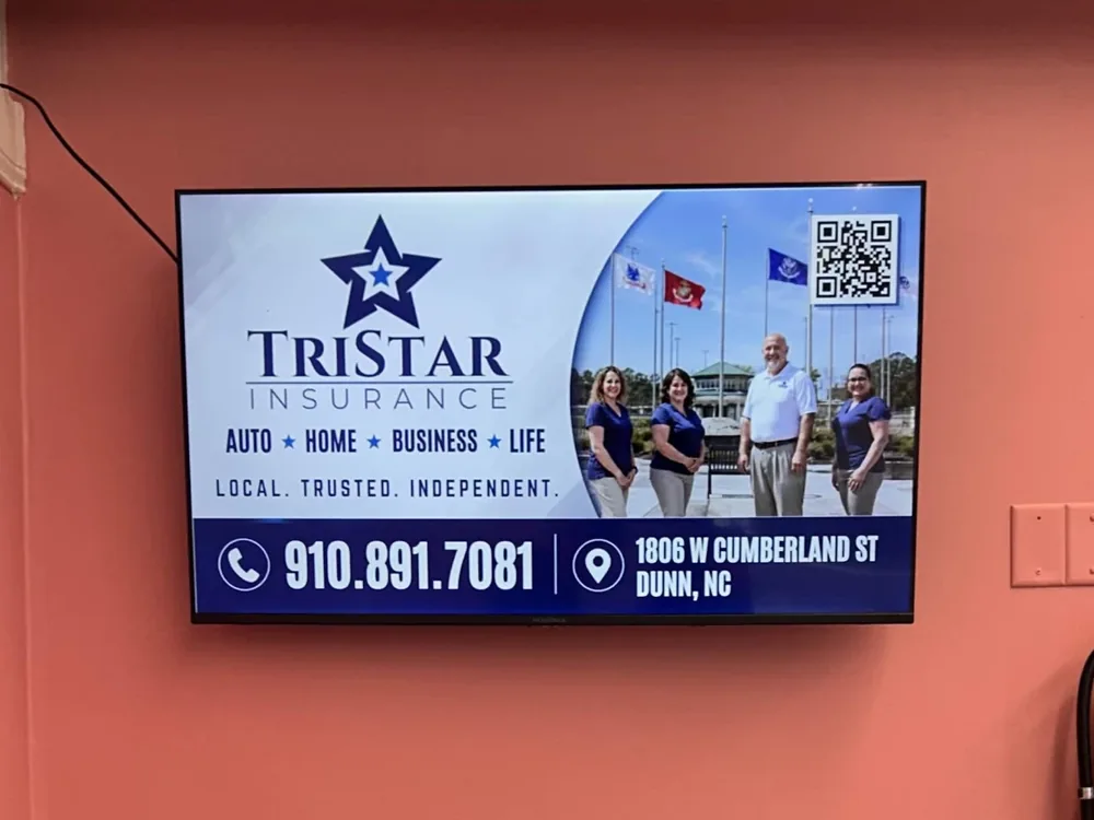 Digital billboard screen playing a TriStar Insurance ad above the seating area of a local diner