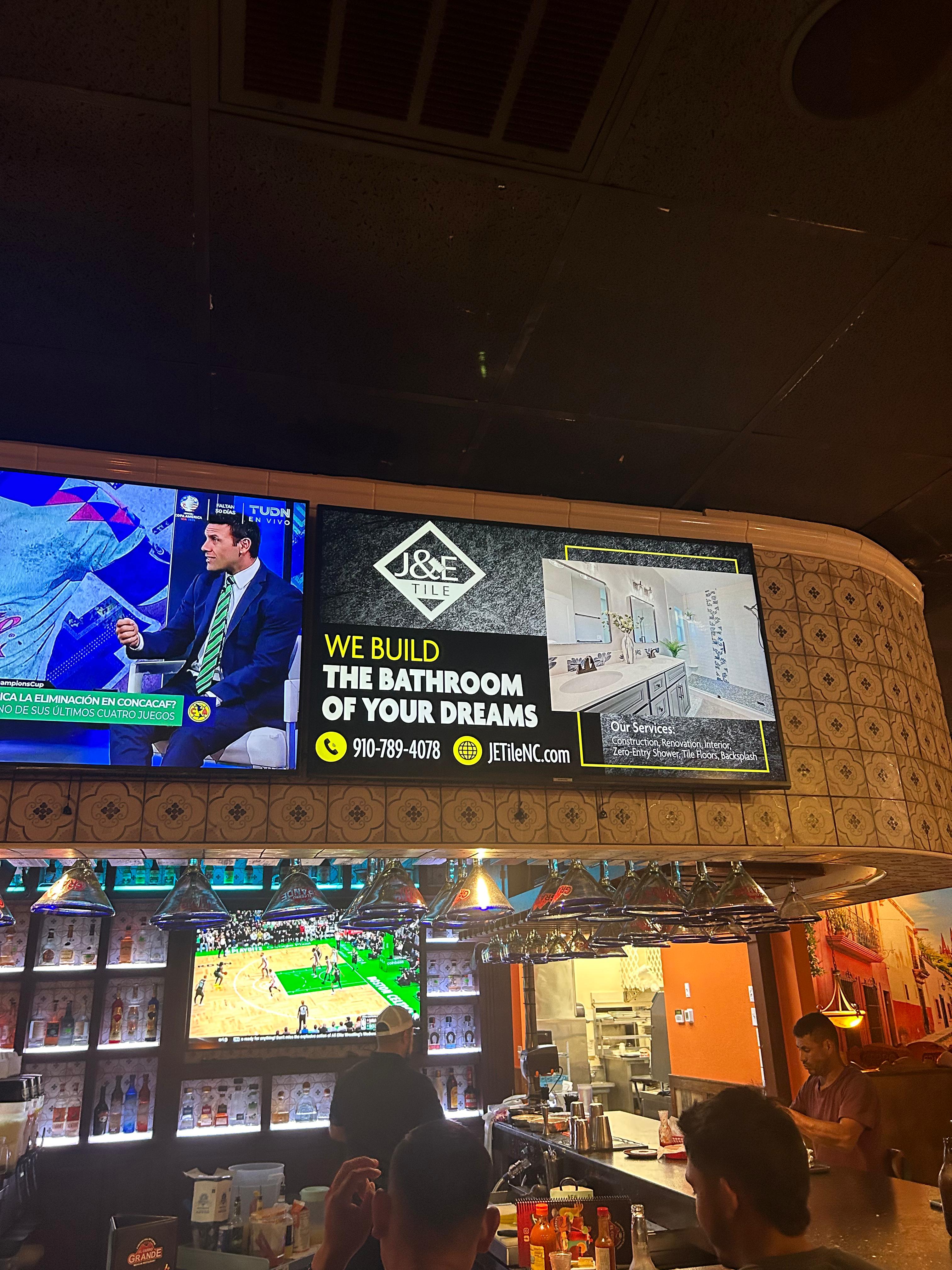 Digital billboard mounted on a venue wall promoting local advertising